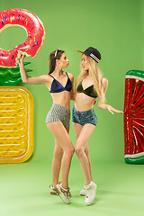 Image showing Cute girls in swimsuits posing at studio. Summer portrait caucasian teenagers on green background.