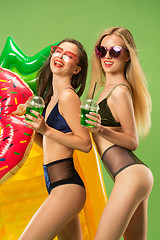 Image showing Cute girls in swimsuits posing at studio. Summer portrait caucasian teenagers on green background.