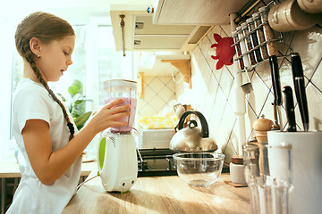 Image showing The happy smiling caucasian girl in the kitchen preparing breakfast