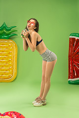 Image showing Cute girl in swimsuit posing at studio. Summer portrait caucasian teenager on green background.