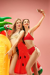 Image showing Cute girls in swimsuits posing at studio. Summer portrait caucasian teenagers on pink background.