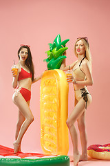Image showing Cute girls in swimsuits posing at studio. Summer portrait caucasian teenagers on pink background.