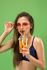 Image showing Cute girl in swimsuit posing at studio. Summer portrait caucasian teenagers on green background.