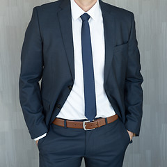 Image showing Torso of a businessman standing with hands clenched in middle position in a classic navy blue suit.