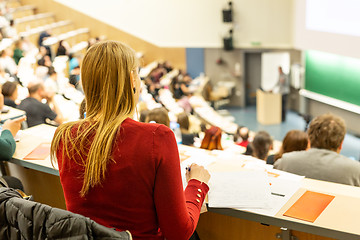 Image showing Female student attending faculty lecture workshop making notes.