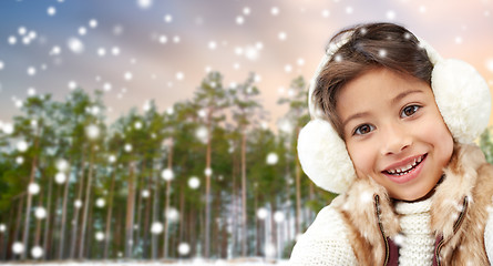 Image showing little girl wearing earmuffs over winter forest