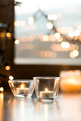 Image showing candles burning on window sill with garland lights