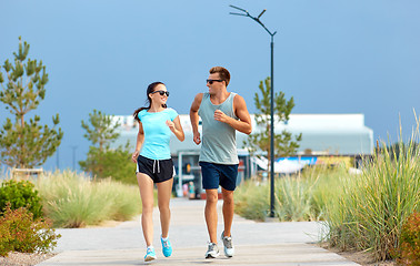 Image showing couple in sports clothes running along on beach