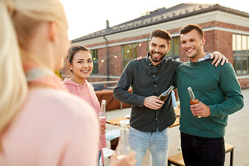 Image showing happy friends with drinks hugging at rooftop party