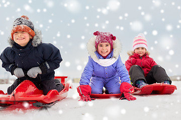 Image showing happy little kids sliding down on sleds in winter