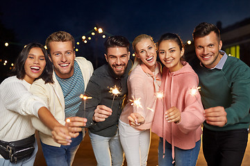 Image showing happy friends with sparklers at rooftop party
