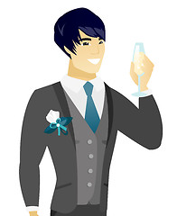 Image showing Young asian groom holding glass of champagne.