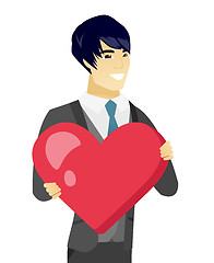 Image showing Young asian groom holding a big red heart.