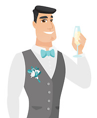 Image showing Young caucasian groom holding glass of champagne.