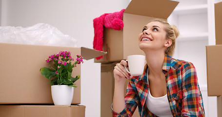 Image showing woman with many cardboard boxes sitting on floor