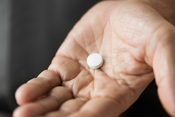 Image showing close up of senior man hand with pill