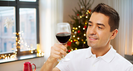 Image showing happy man drinking red wine at home on christmas