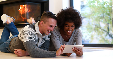 Image showing multiethnic couple using tablet computer on the floor