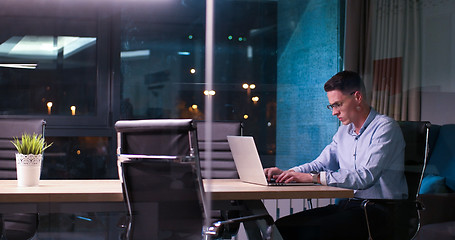 Image showing man working on laptop in dark office