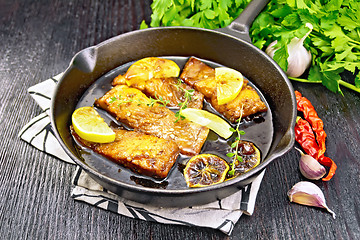 Image showing Salmon with sauce in pan on wooden board