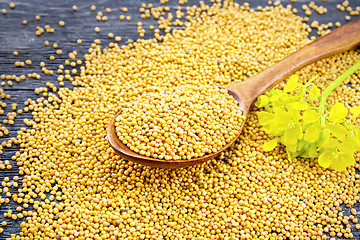 Image showing Mustard seeds in spoon with flower on board