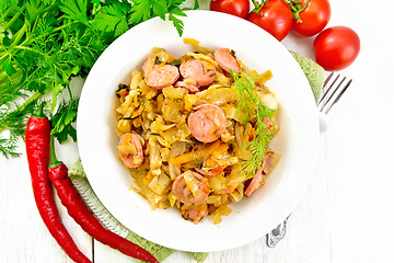 Image showing Cabbage stew with sausages in white plate on light board top