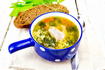 Image showing Soup with couscous and spinach in blue bowl on light board