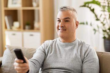 Image showing man with remote control watching tv at home