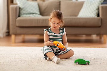 Image showing happy baby girl playing with toy car at home