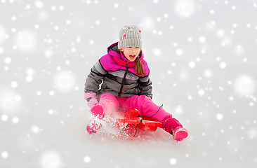 Image showing happy little girl sliding down on sled in winter