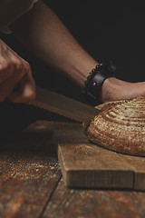 Image showing Man slicing tasty fresh bread.