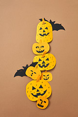 Image showing Different handcraft scary pumpkins and bats on a brown background with space for text. Creative composition for Halloween. Flat lay