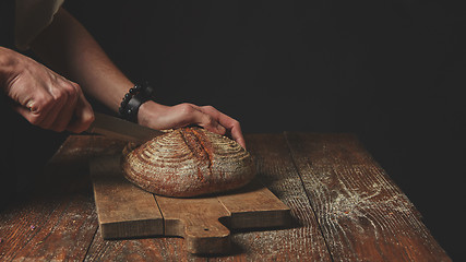 Image showing Men\'s hands cut bread