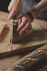 Image showing Woman\'s hands cut fresh bread