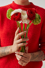 Image showing Young girl in a red sweater holding a bouquet of fresh flowers.