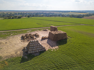 Image showing Green field with large haystacks and tractor on a sunny day. Aerial view from the drone