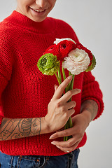 Image showing Beautiful girl in a red sweater with flowers in hands on a white background