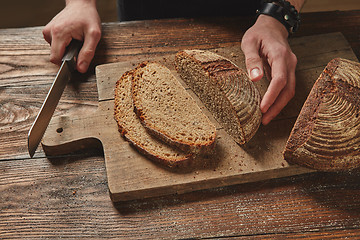 Image showing Man slicing tasty fresh bread.