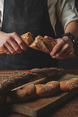 Image showing Male hands break the baguette