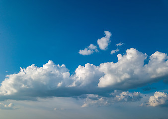 Image showing White fluffy clouds in the blue sky at sunset in the summer day.