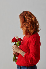 Image showing Young woman with lush red hair with a bunch of fresh Ranunculus on gray background with copy space.