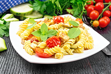 Image showing Fusilli with chicken and tomatoes in plate on black wooden board