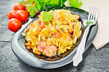 Image showing Cabbage stew with sausages in plate on black board