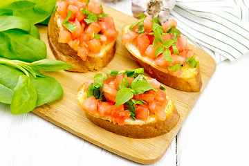 Image showing Bruschetta with tomato and spinach on white wooden table