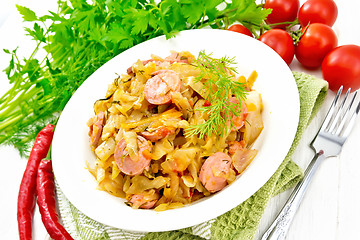 Image showing Cabbage stew with sausages in white plate on light board