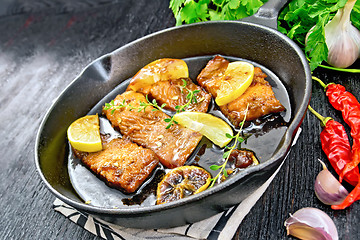 Image showing Salmon with sauce in pan on black board