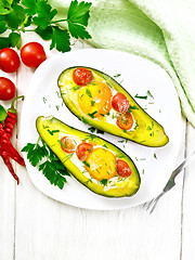 Image showing Scrambled eggs with tomatoes in avocado on light board top