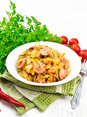 Image showing Cabbage stew with sausages in plate on white board