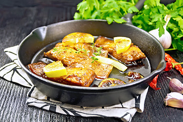 Image showing Salmon with sauce in pan on black wooden board