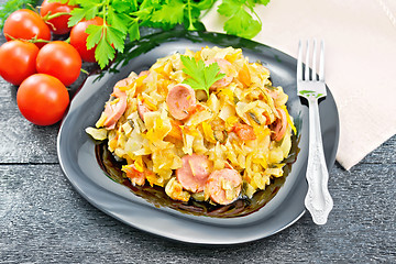 Image showing Cabbage stew with sausages in plate on dark board